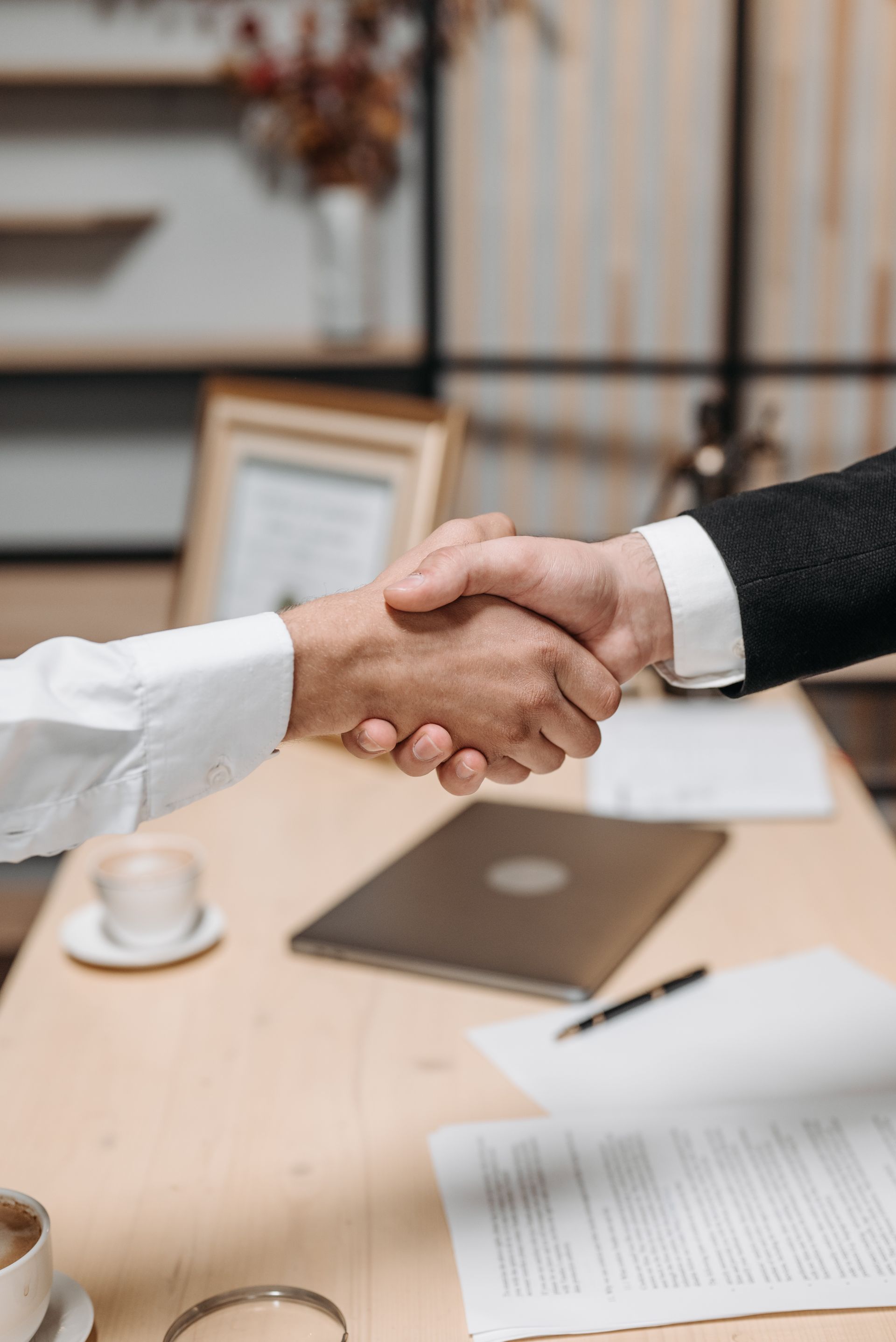 Two professionals shaking hands across a desk