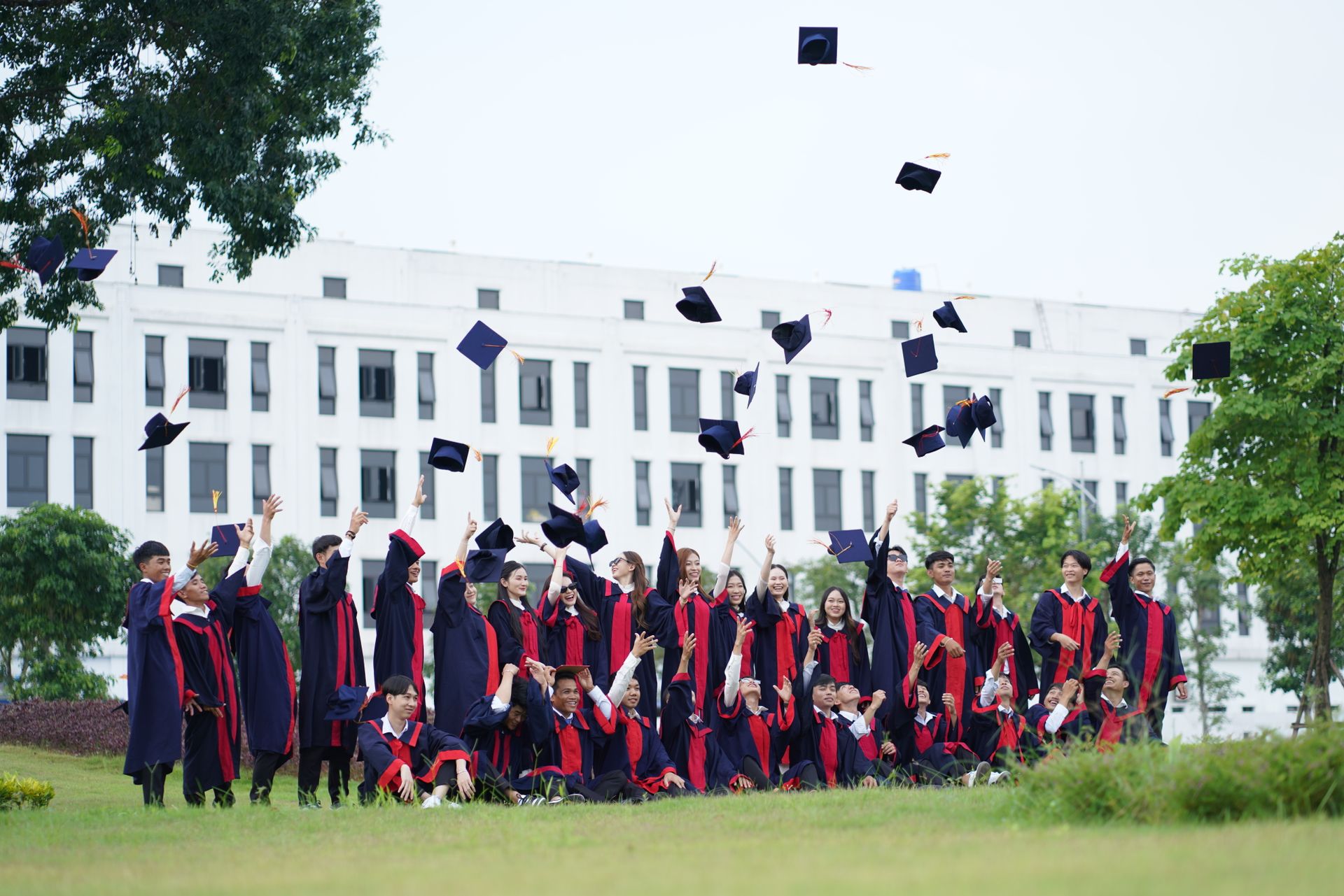 Graduates celebrating by throwing caps into the air outside a university building
