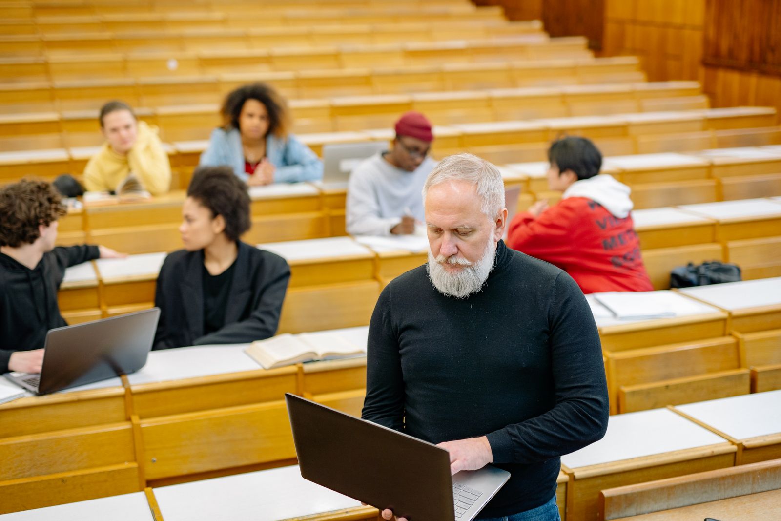 A professor teaching students with laptops in a lecture hall