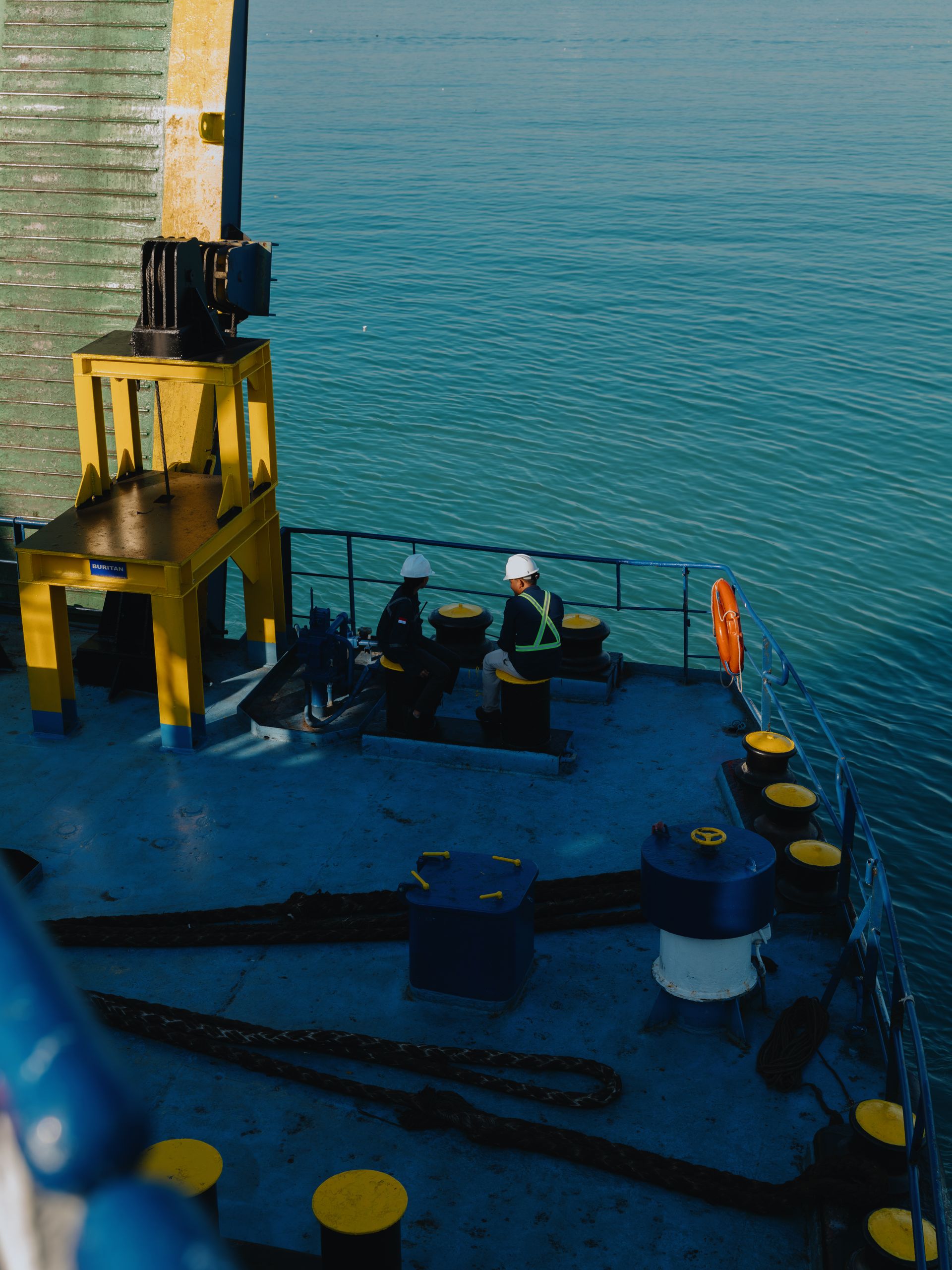 Two seafarers working on the deck of a cargo ship