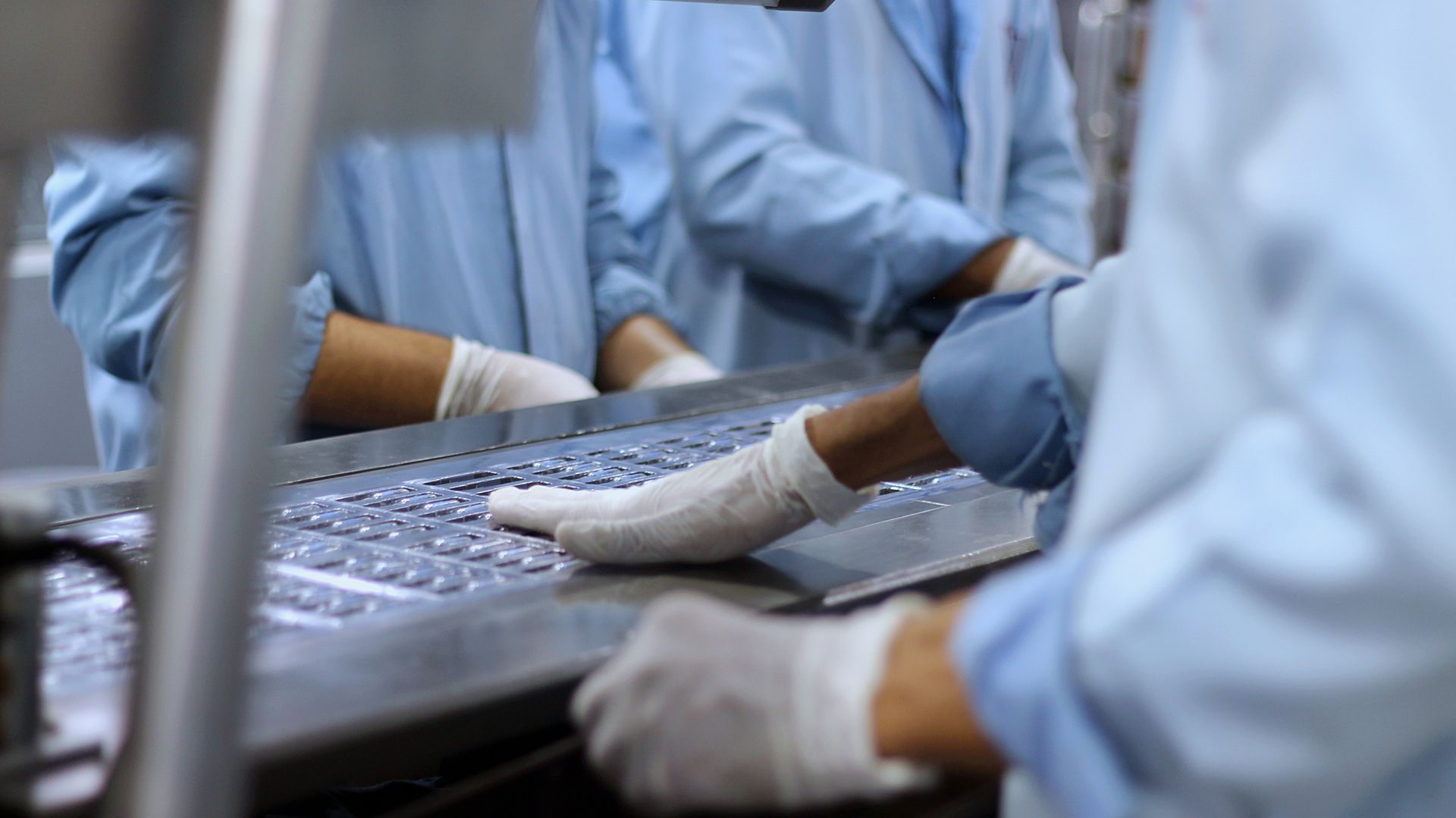 Workers on a pharmaceutical production line packaging tablets