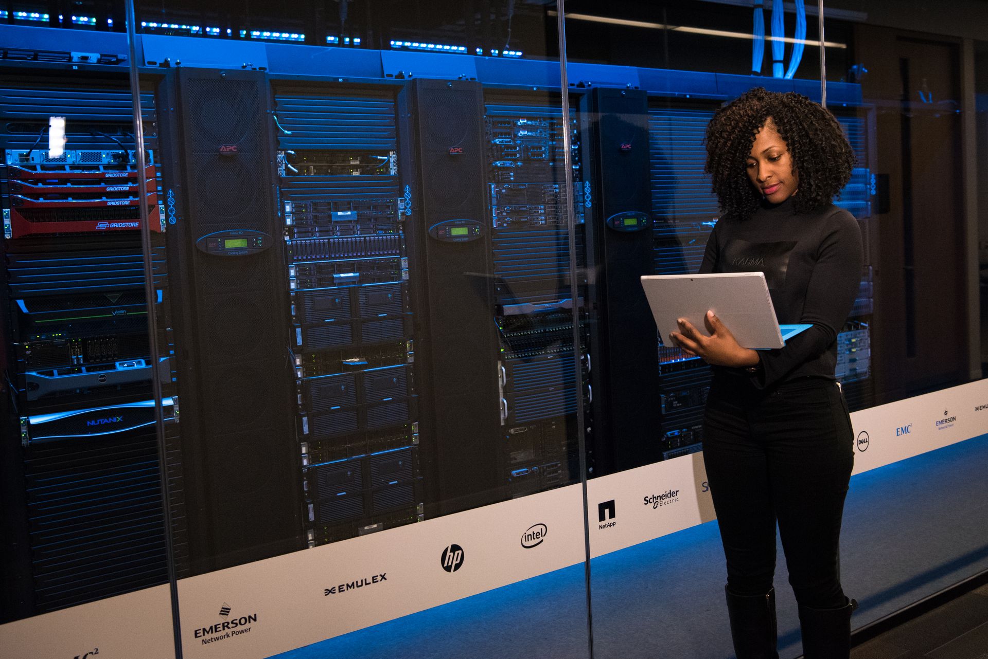 An engineer monitoring data servers with a laptop in a server room