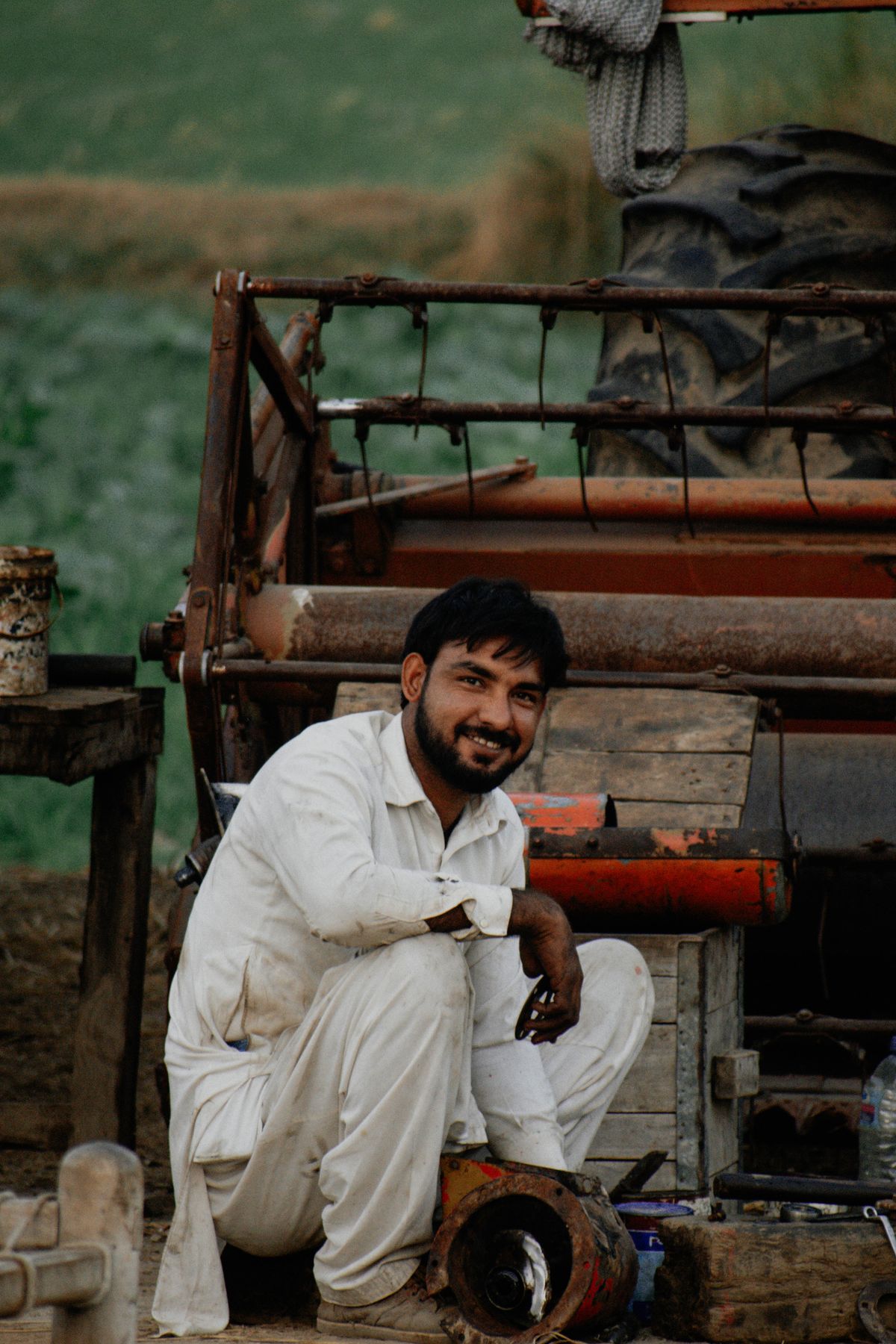 A farmer repairing agricultural machinery in a field