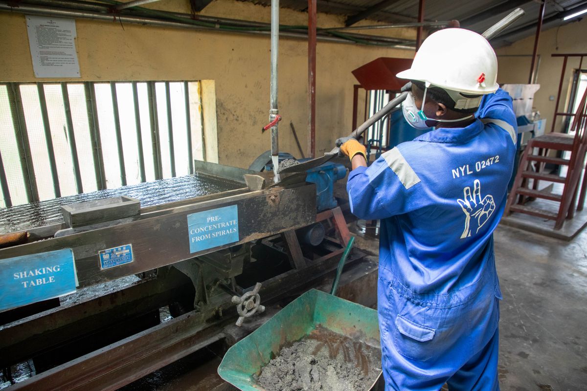 A worker in blue overalls operating an ore processing table