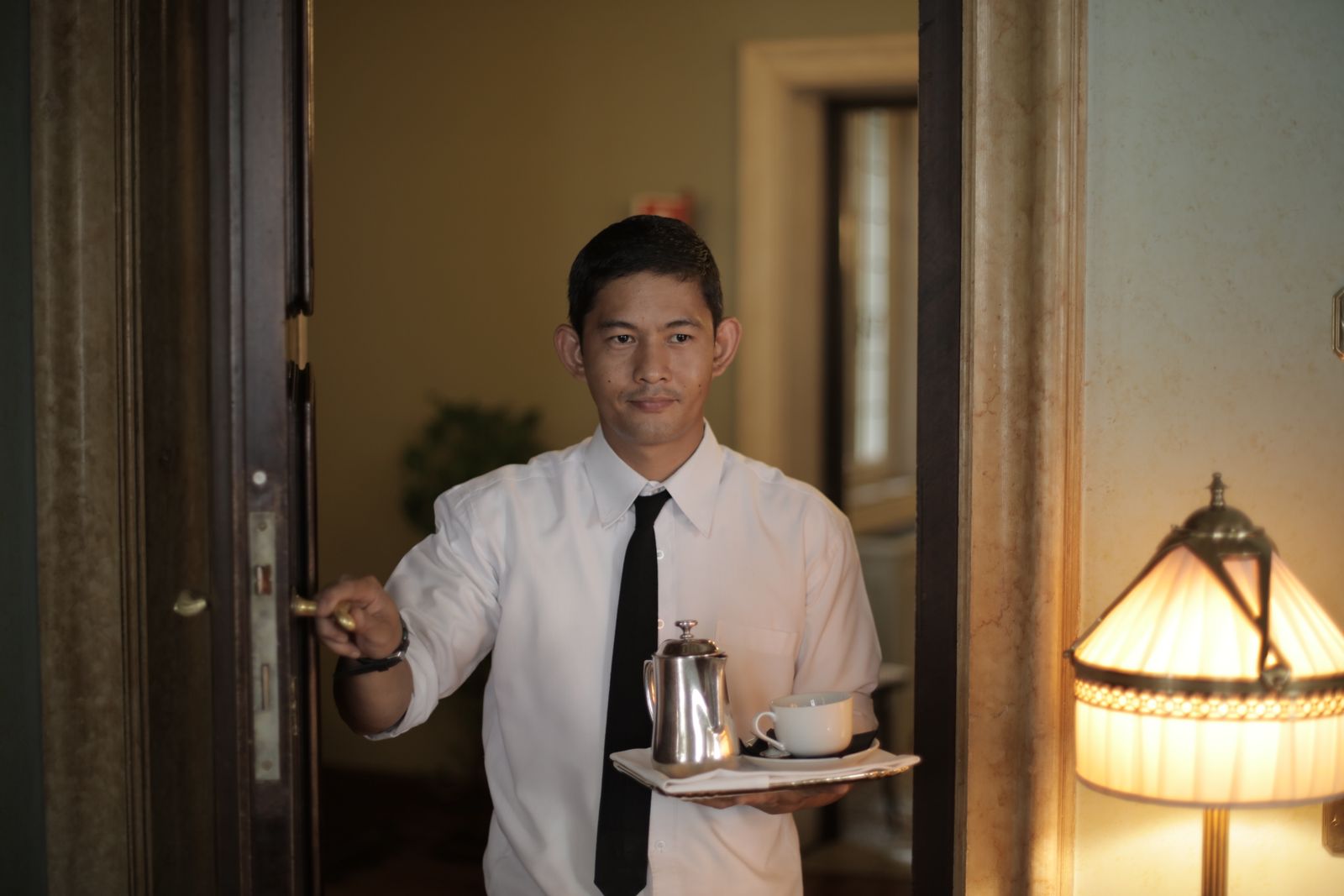 A staff member welcoming a guest with room-service coffee