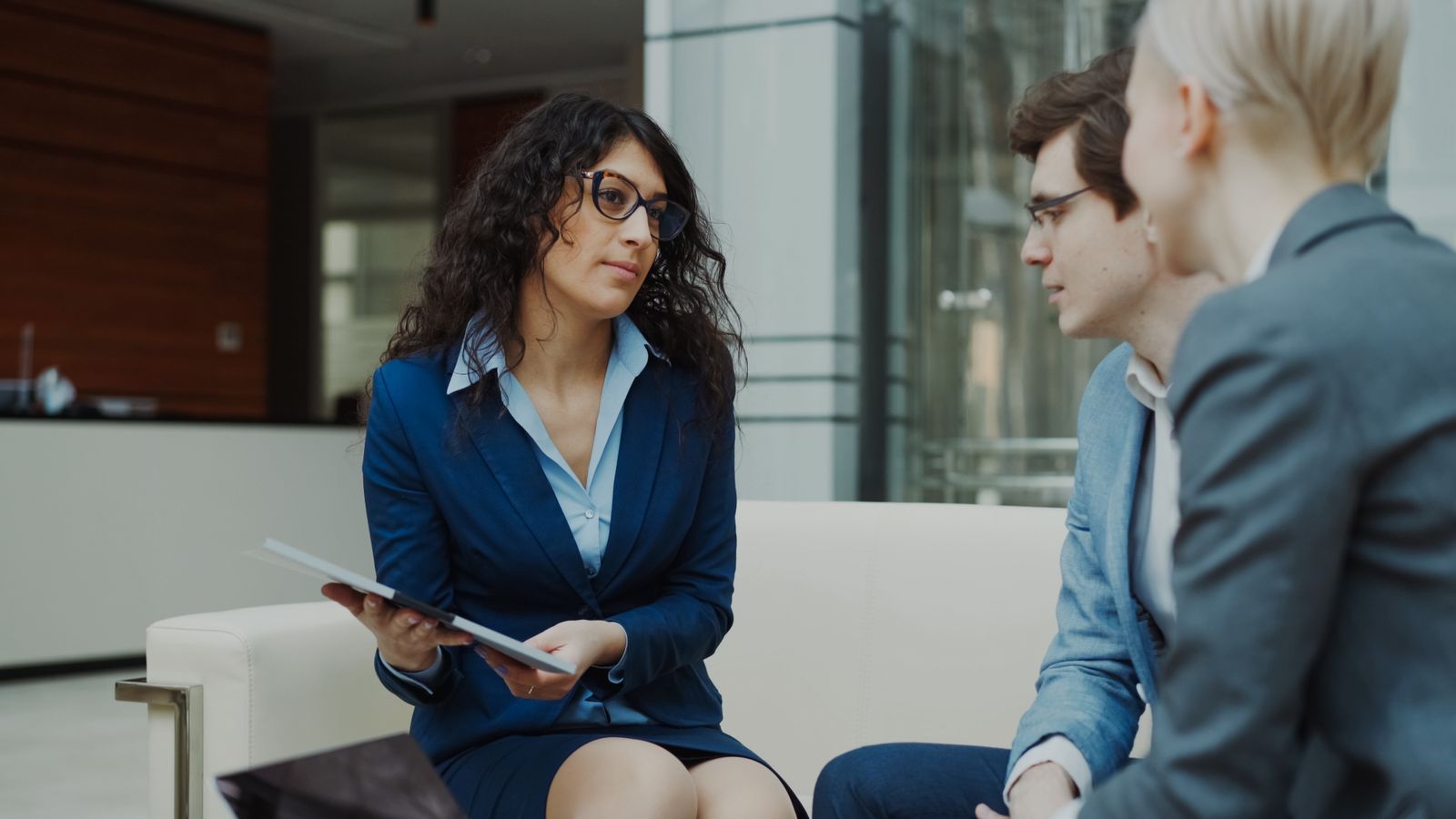 Three professionals discussing work in a modern office lounge