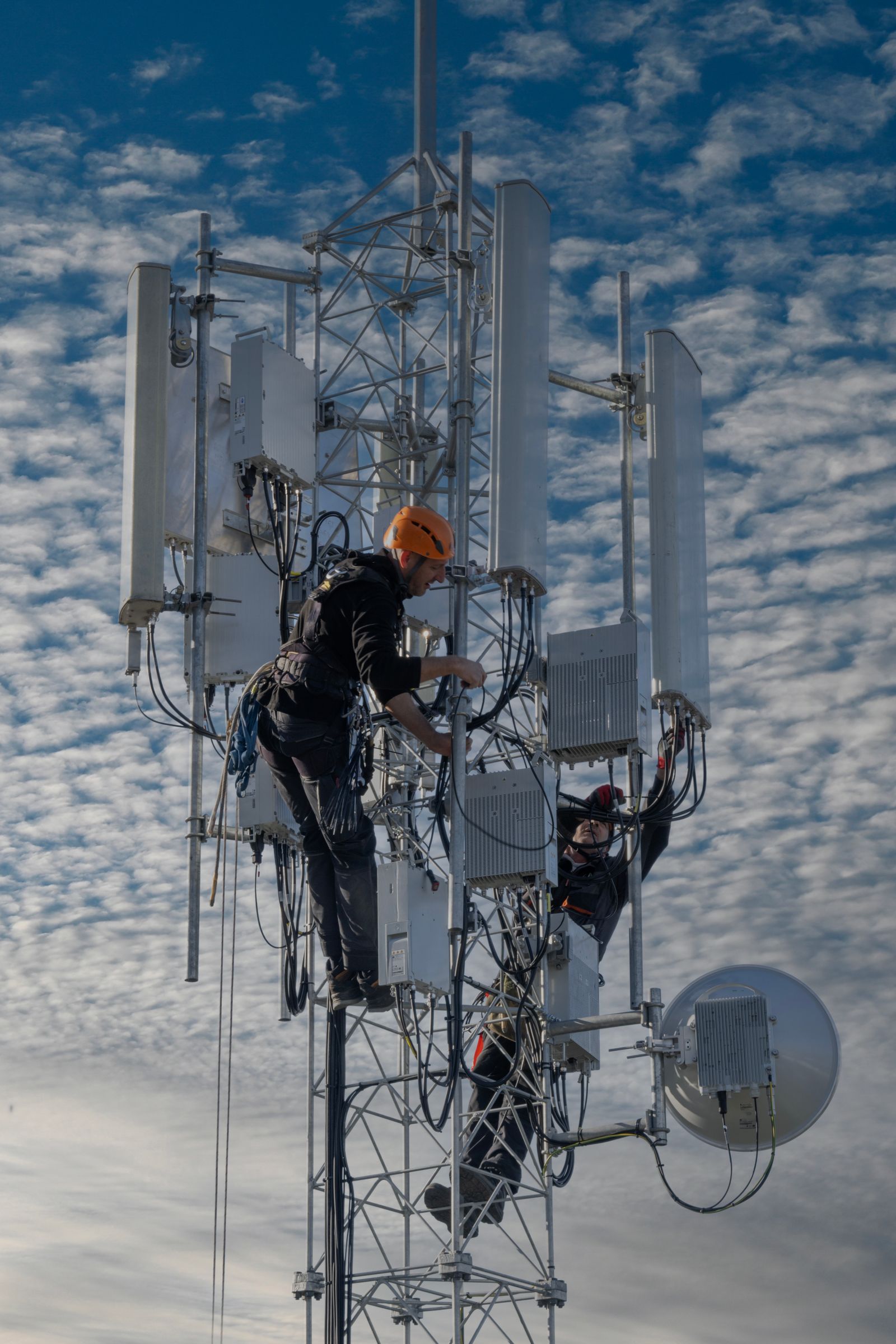 Two technicians working on a network tower
