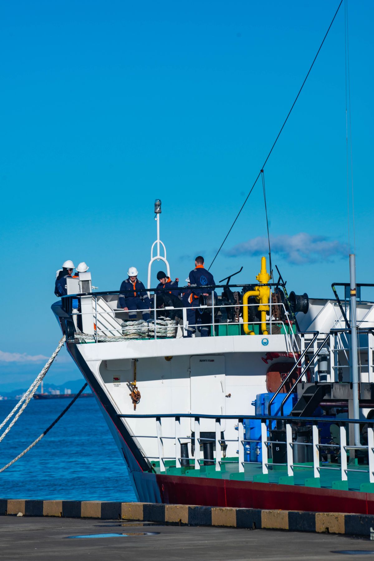 Sailors in uniform managing a commercial ship docked at a harbor