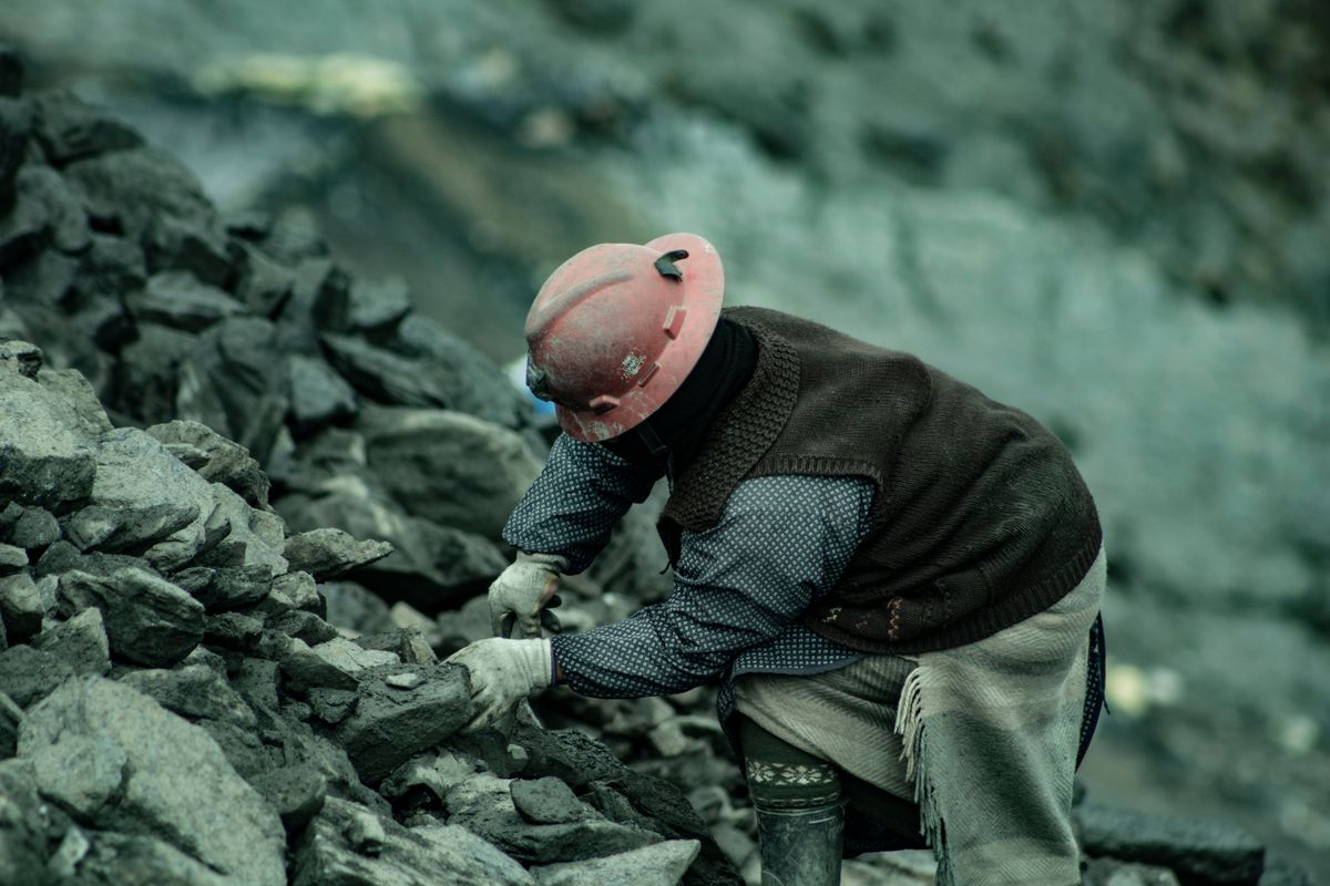 A miner in a hard hat working amidst rocky terrain