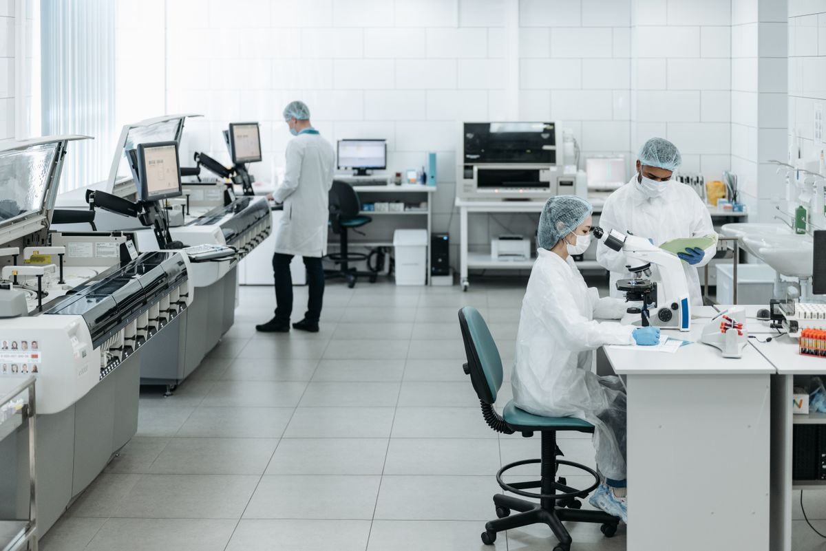 Researchers in lab coats conducting experiments with advanced equipment