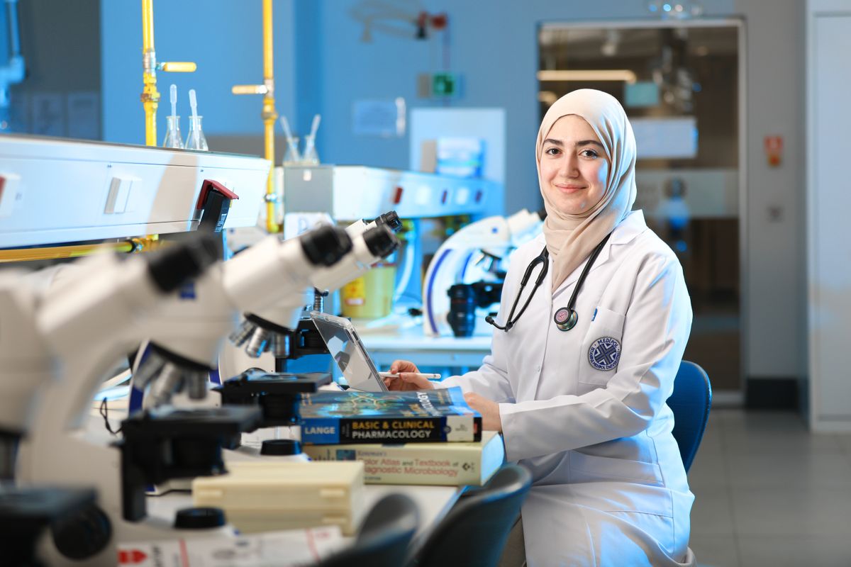 A female scientist conducting research with a microscope and reference books